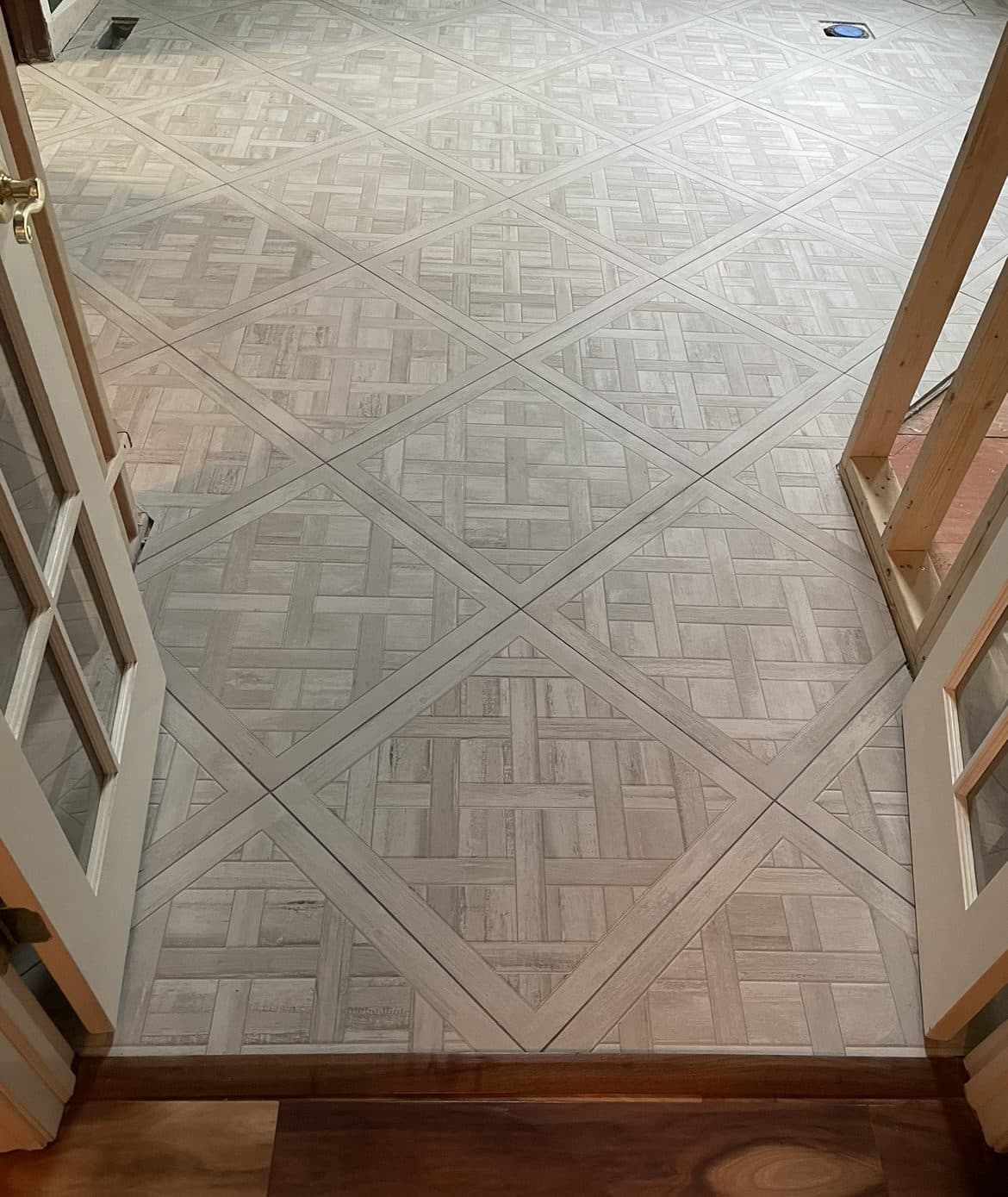 Decorative interlocking basket-weave pattern tile entryway installation with hardwood transition in Northeast Ohio home