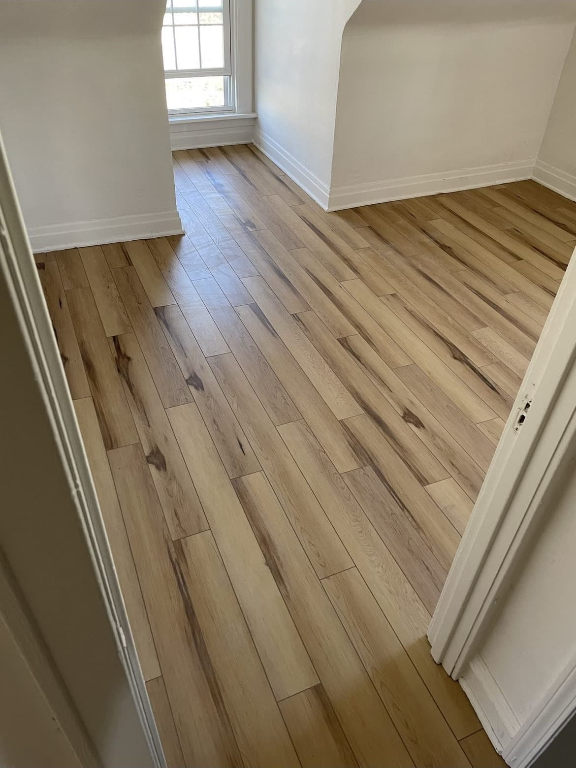 Light natural wood-look plank flooring installation in bright open foyer in Northeast Ohio home
