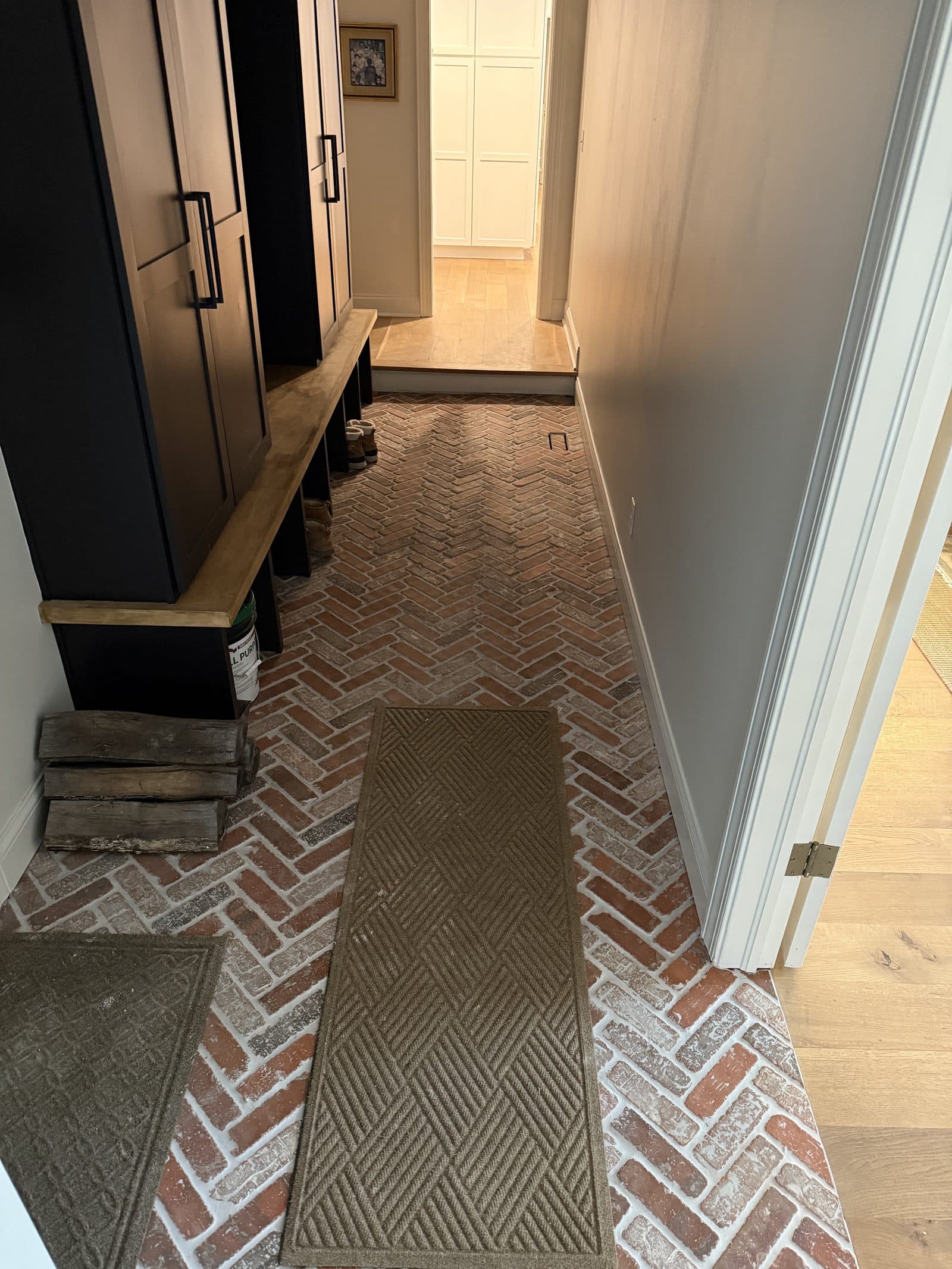 Red brick herringbone entryway floor with custom built-in bench and dark shaker cabinetry in Lake County Ohio