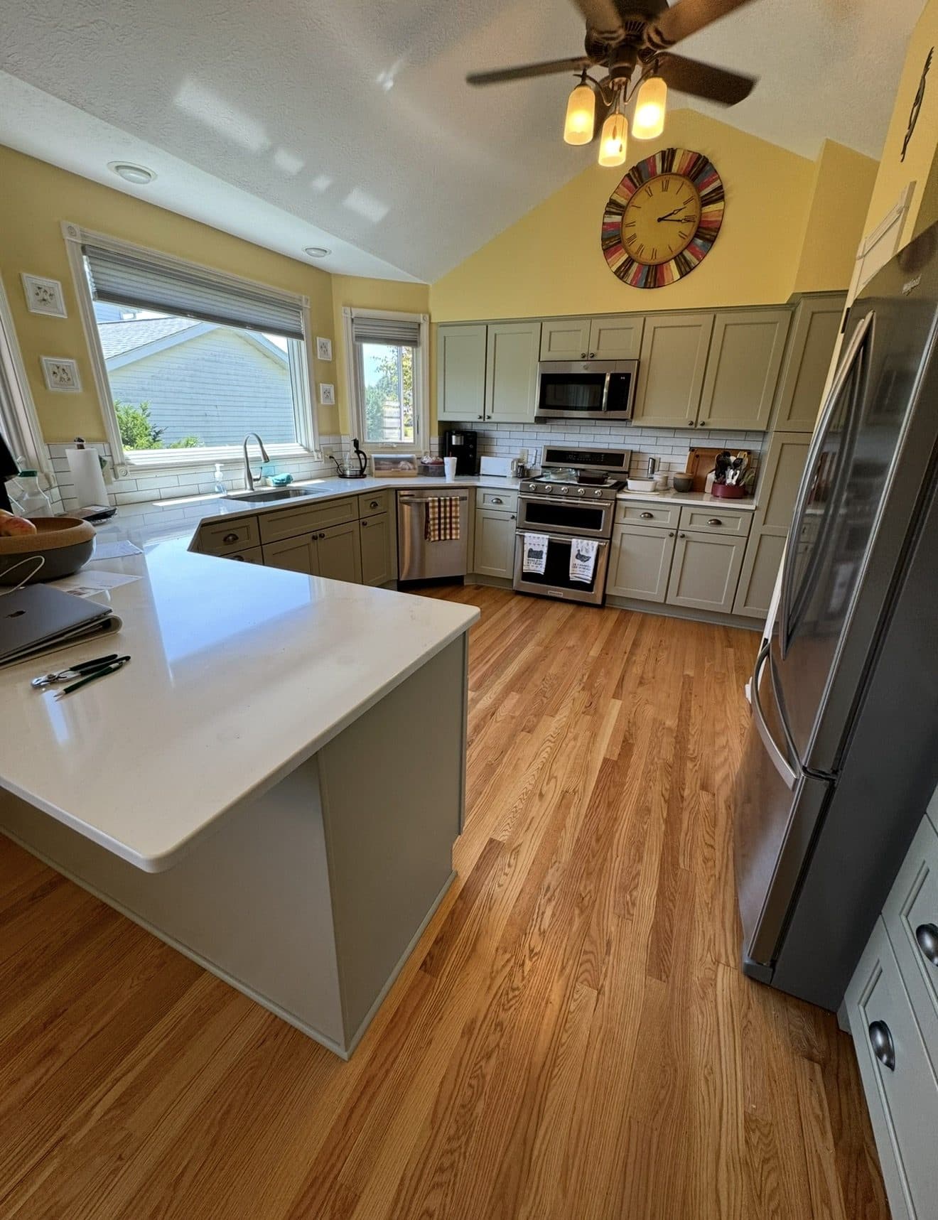 Kitchen remodel with sage green raised-panel cabinets, white subway tile backsplash, Calacatta quartz island, and oak hardwood floors in Northeast Ohio