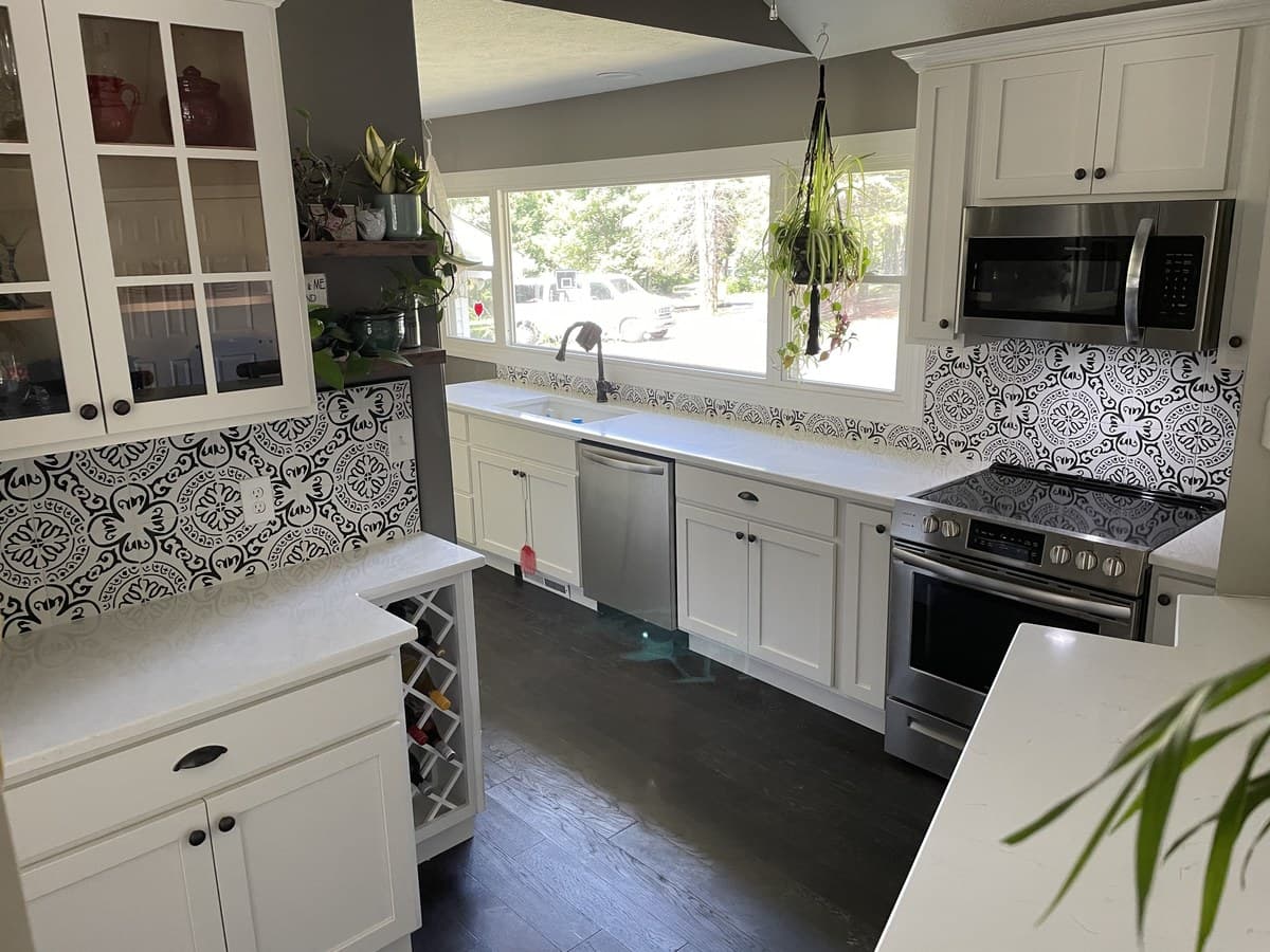 Full kitchen remodel with white shaker cabinets, bold black-and-white encaustic cement tile backsplash, white quartz countertops, and dark hardwood floors in Northeast Ohio
