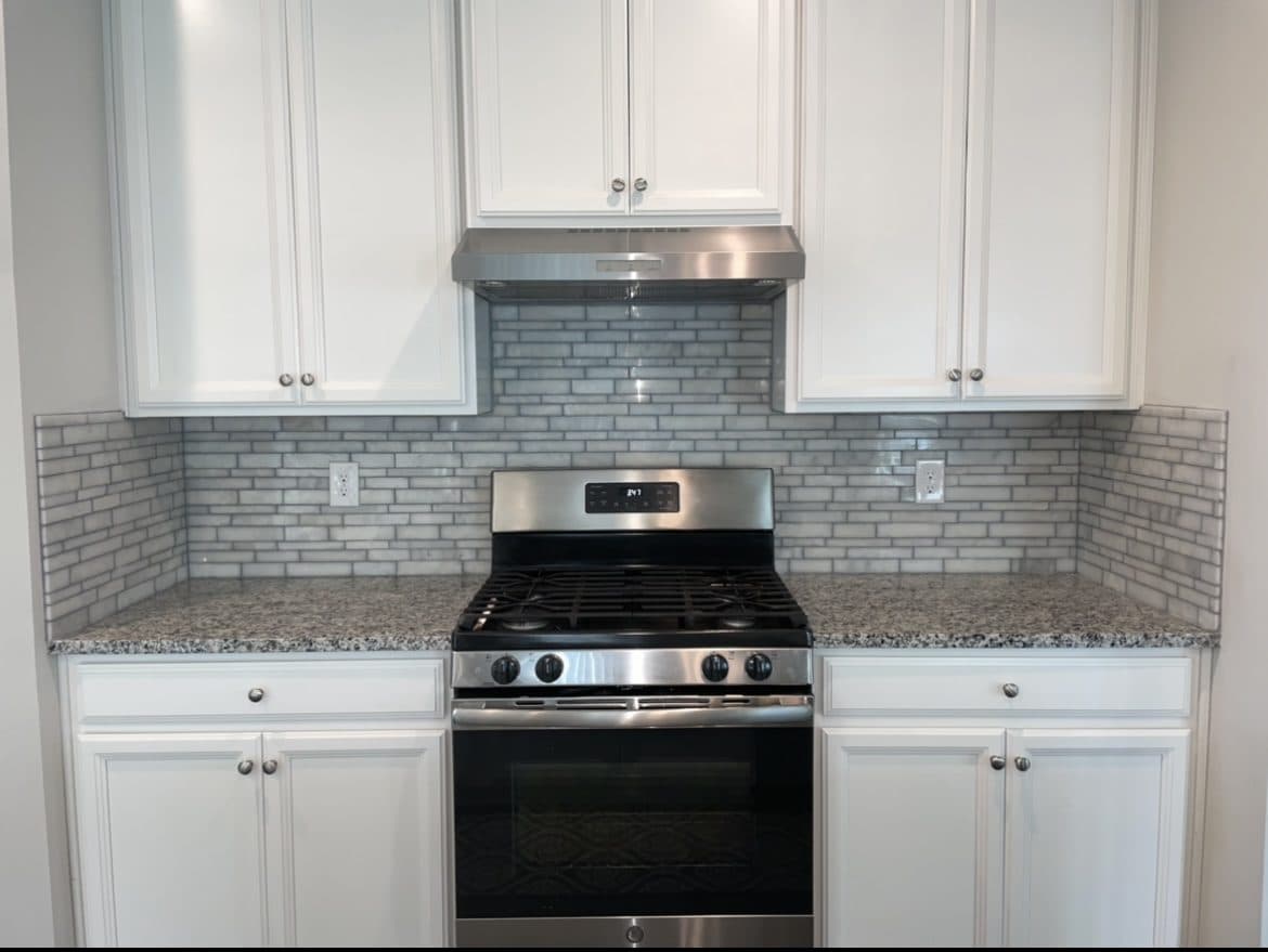 Kitchen backsplash upgrade with white shaker cabinets, gray marble mini-brick tile, and granite countertops in Lake County Ohio