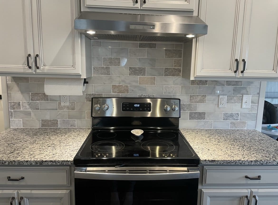 Kitchen backsplash and countertop upgrade with travertine-look tile, white raised-panel cabinets, and granite in Cuyahoga County