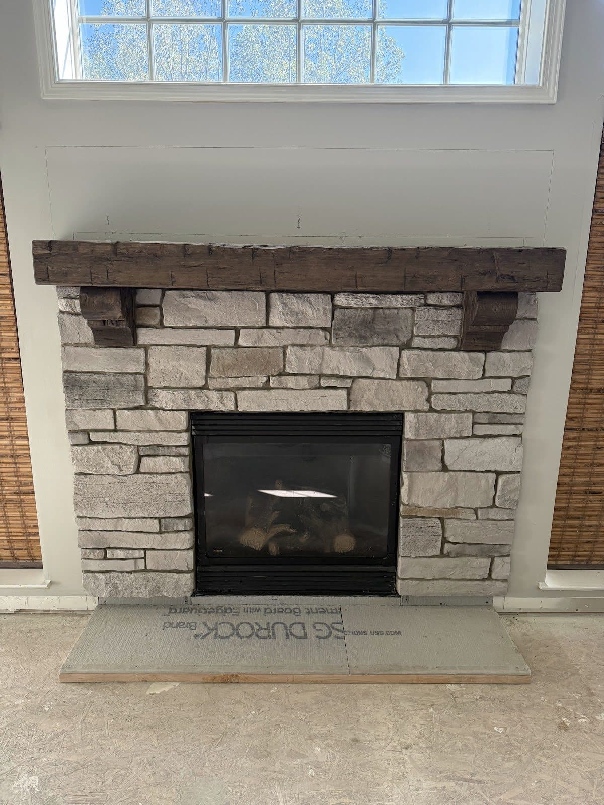 Fireplace remodel with light ledger stone surround and rustic reclaimed wood beam mantel in Northeast Ohio home